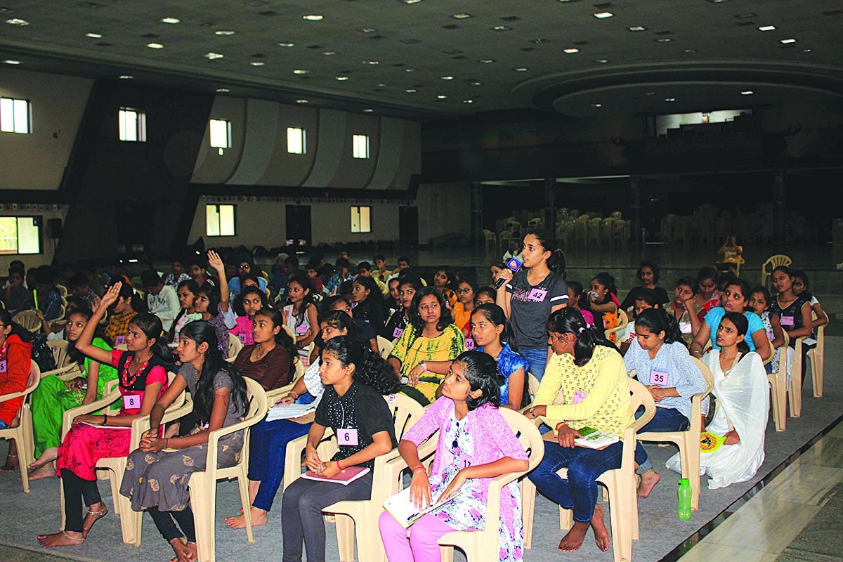 Young people at a session in the hall, one asking a question